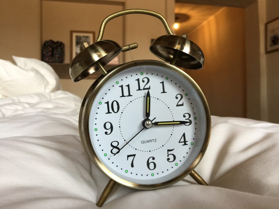 better sleep habits shown as a calm evening routine with warm lamp light, a notebook, a glass of water, and a quiet bedroom